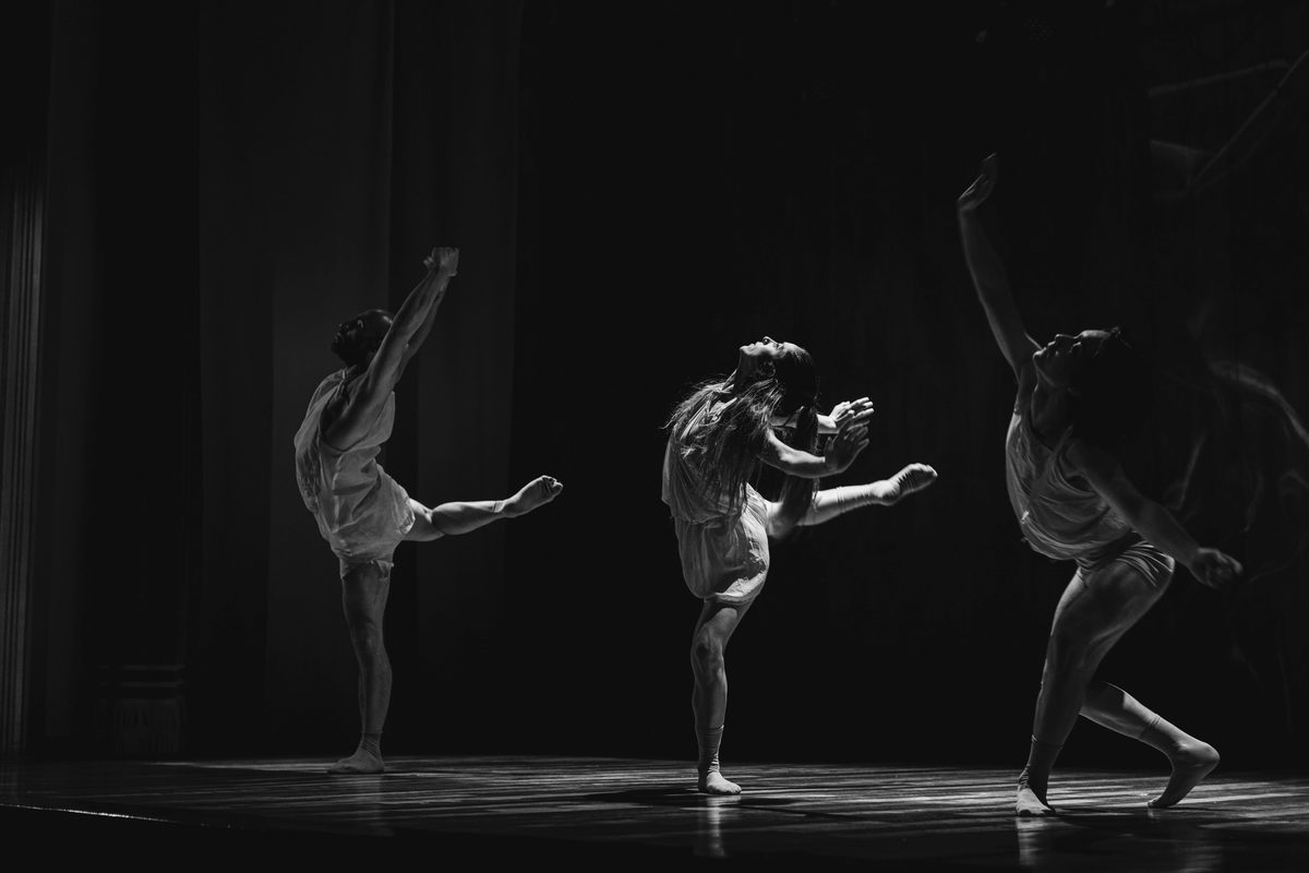 Three dancers rehearsing under studio lights in a dance and drama space