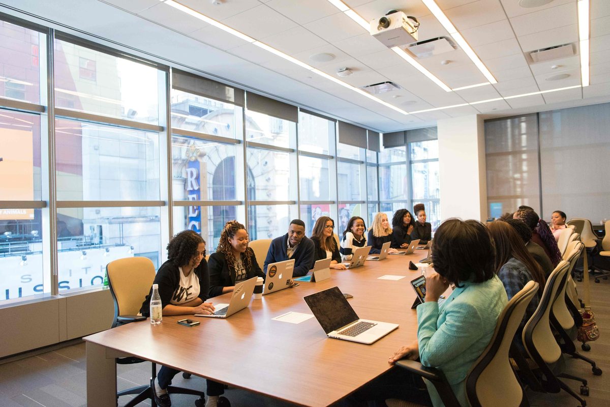 A meeting room with a long table and people seated around it