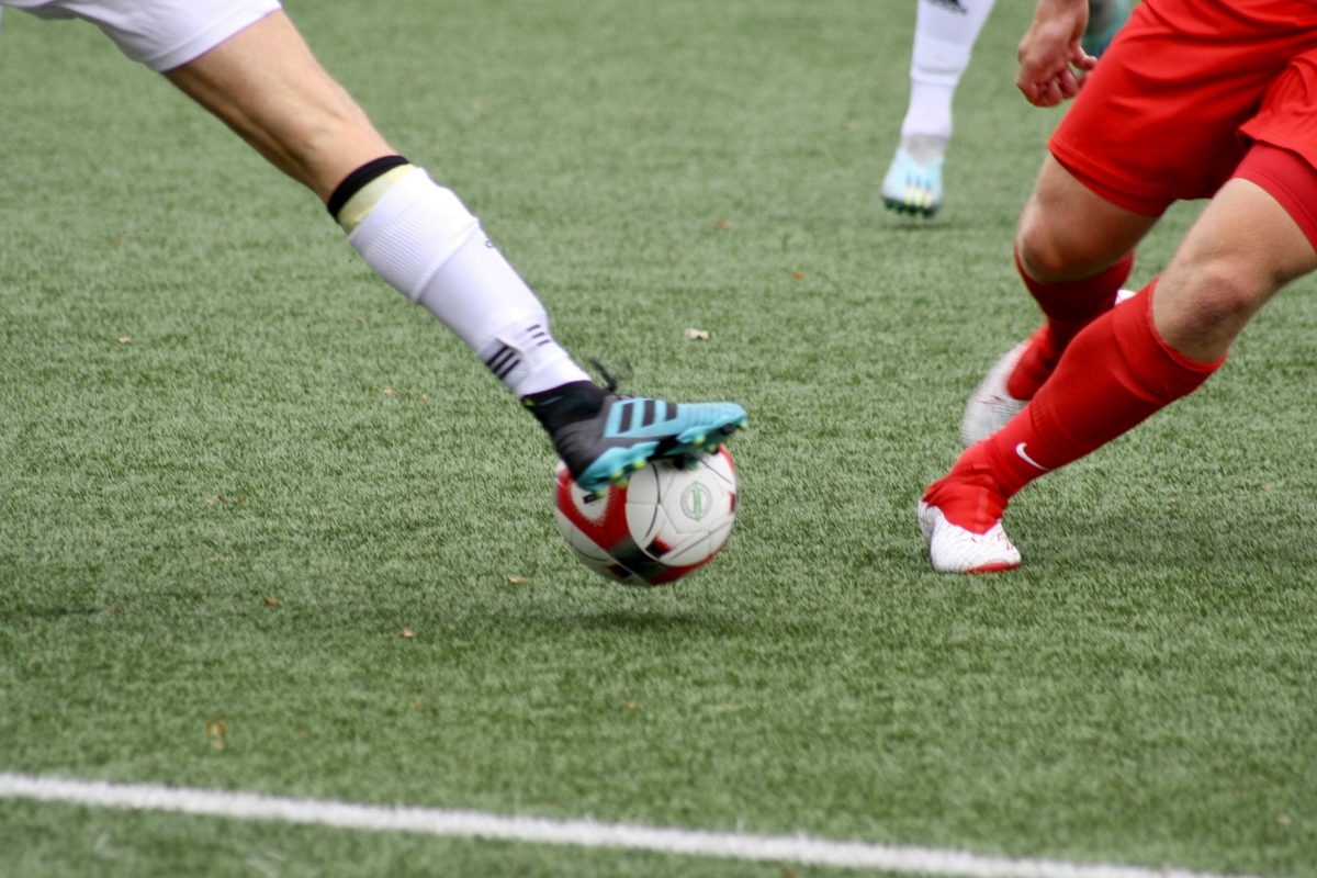 Boots and a football on the marked surface of an all-weather pitch